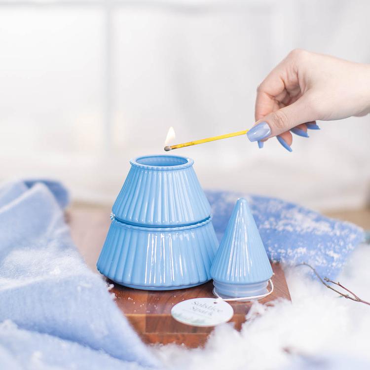Ice Blue Tiered Glass Tree Jar with top level removed and a lit match lighting the candle