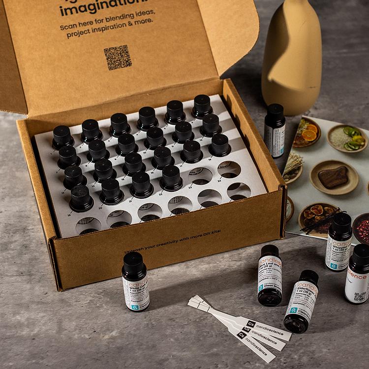 An open 30 pc luxury collection box showing blotter strips, fragrances, and a booklet on a grey tabletop. 