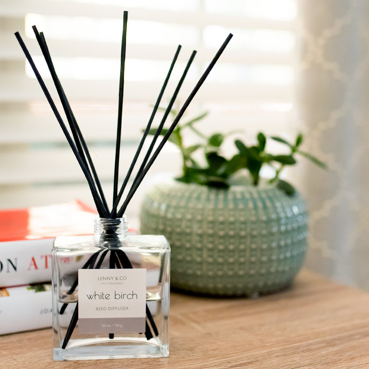 Square Glass Reed Diffuser Bottle with Black Rattan Reeds on bookshelf