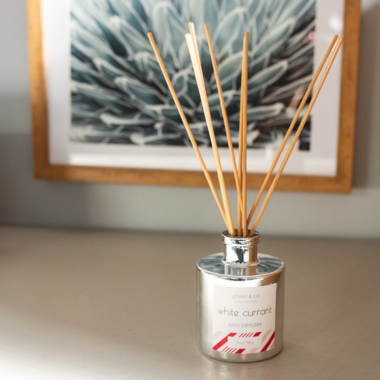 Silver Round Reed Diffuser Bottle with Natural Rattan Reeds sitting on a counter