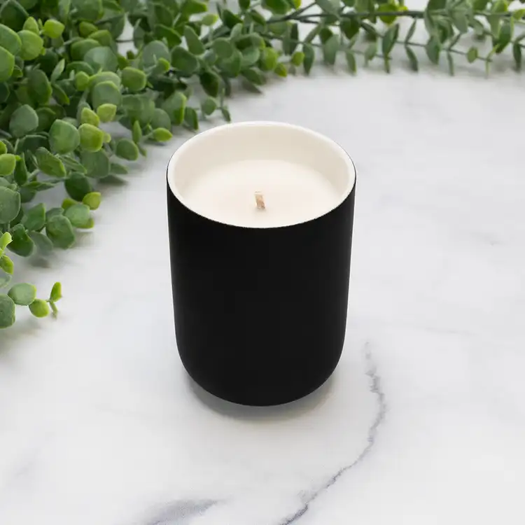Black Dream Ceramic Tumbler Jar Candle in front of greenery