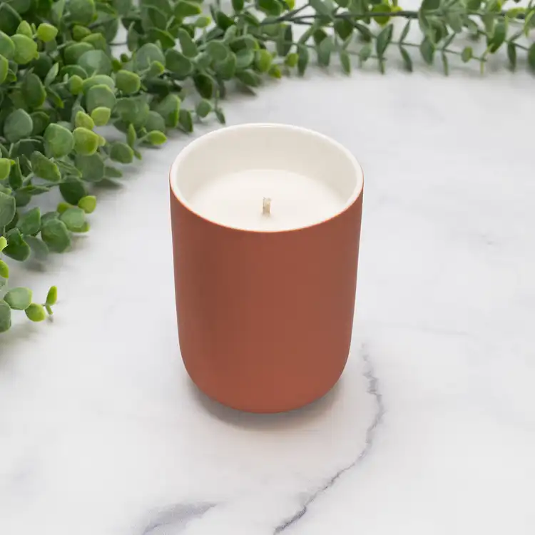 Desert Coral Dream Ceramic Tumbler Jar Candle in front of greenery