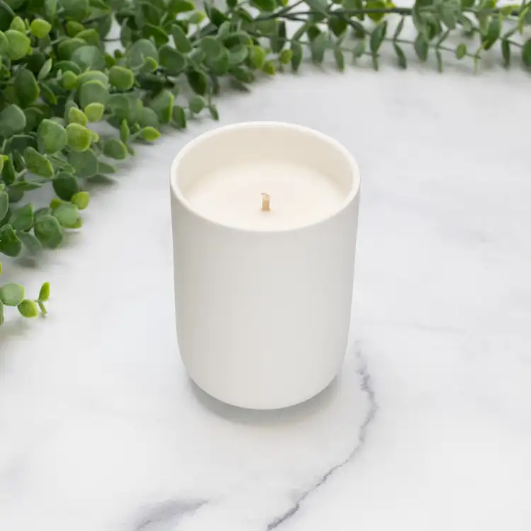 White Dream Ceramic Tumbler Jar Candle in front of greenery