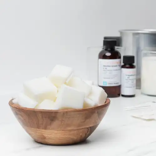 CandleScience Coconut Apricot Wax in a bowl with fragrance oils in the background