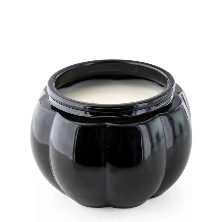 A black pumpkin jar without the lid filled with a candle