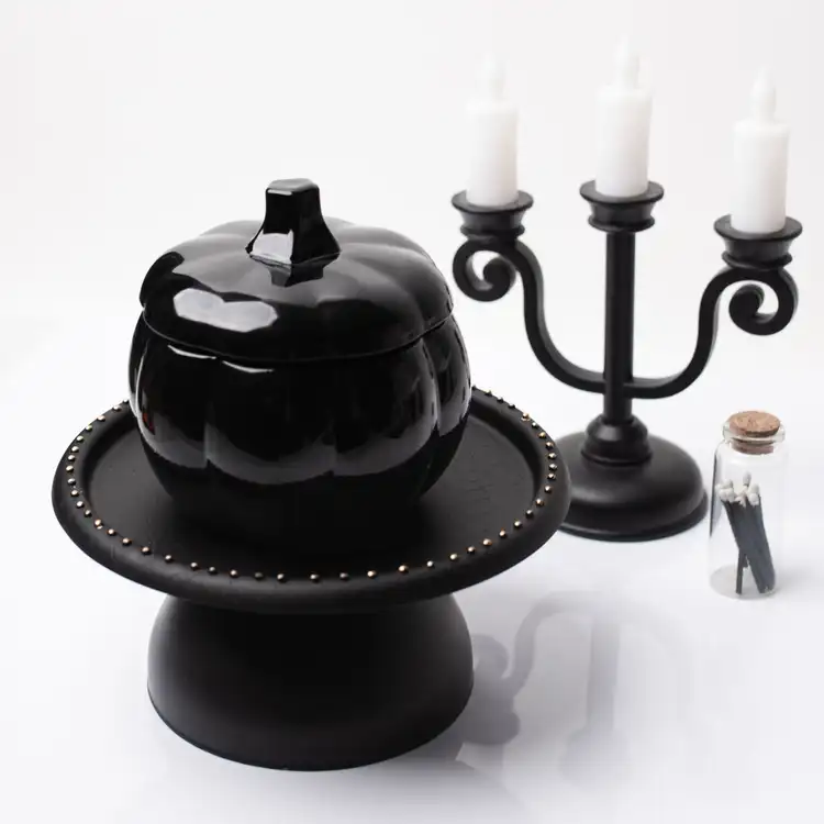 A black pumpkin jar with stem lid with a candelabra
