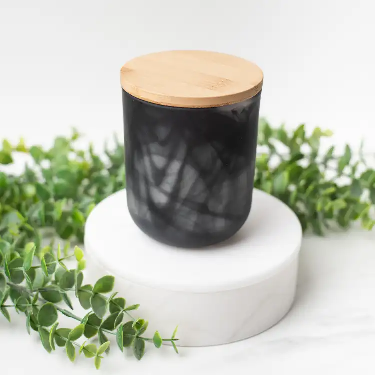 Frosted Black Swirl Sonoma Tumbler with a Bamboo Lid on a white marble podium surrounded by ivy with a black background.