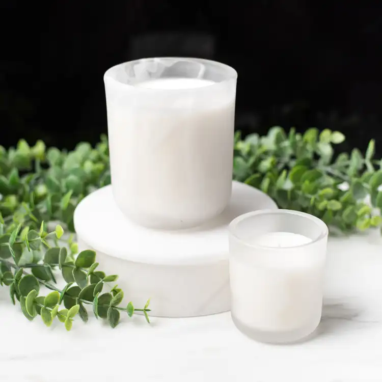 Frosted White Swirl Sonoma Tumbler on a white marble podium paired with a Mini Frosted Sonoma surrounded by ivy with a black background.