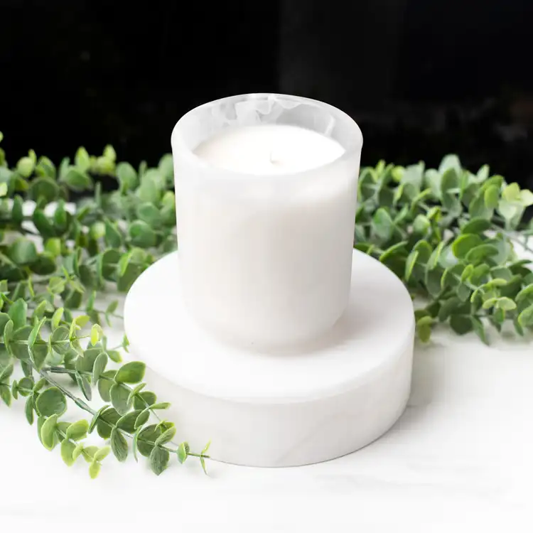 Frosted White Swirl Sonoma Tumbler on a white marble podium surrounded by ivy with a black background.