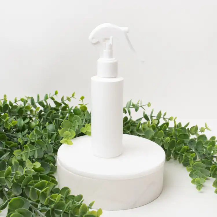 Matte White 4 oz. HDPE Bottle with White Fine Mist Sprayer (24mm-410) beside greenery