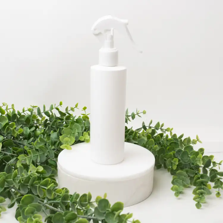 Matte White 8 oz. HDPE Bottle with White Fine Mist Sprayer (24mm-410) beside greenery