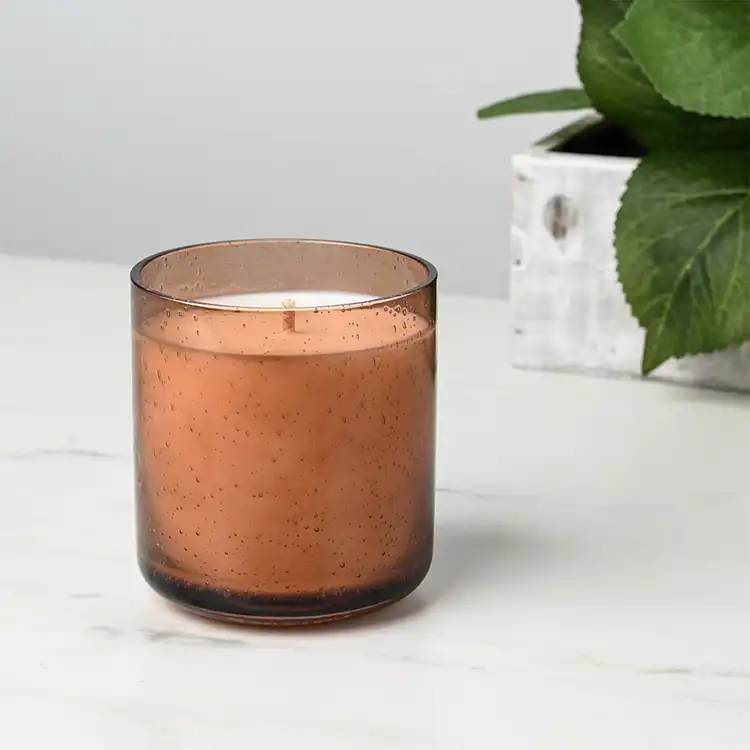 Amber Bubble Tumbler Jar candle in front of plant