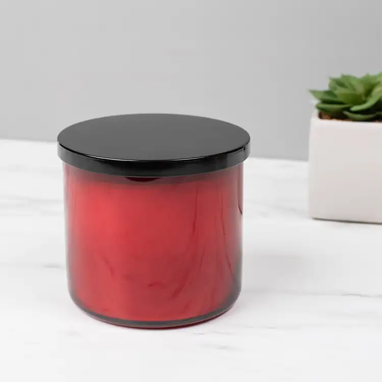 Red 3-Wick Tumbler Jar candle with Black Metal Flat Lid (3-Wick) in front of plant