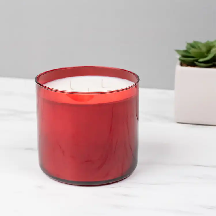 Red 3-Wick Tumbler Jar candle in front of plant