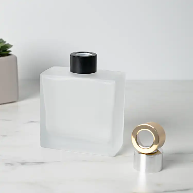 Frosted Square Reed Diffuser Bottle with Matte Black Reed Diffuser Collar on table next to Silver and Gold Reed Diffuser Collar