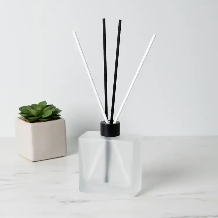 Frosted Square Reed Diffuser Bottle with Matte Black Reed Diffuser Collar and White and Black Fiber Diffuser Reeds on table