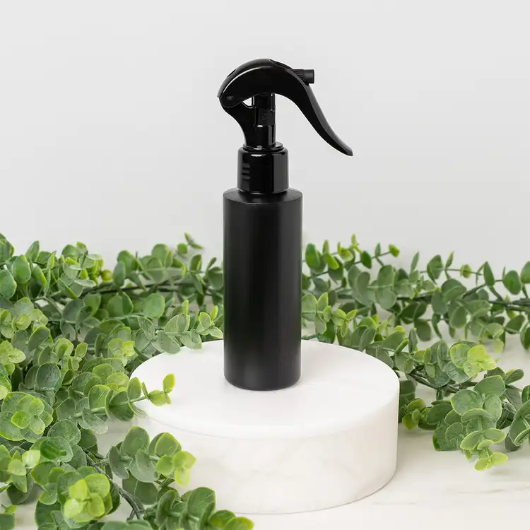 Matte Black 4 oz. HDPE Bottle with Black Fine Mist Sprayer (24mm-410) beside greenery
