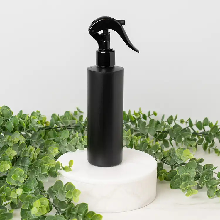 Matte Black 8 oz. HDPE Bottle with Black Fine Mist Sprayer (24mm-410) beside greenery