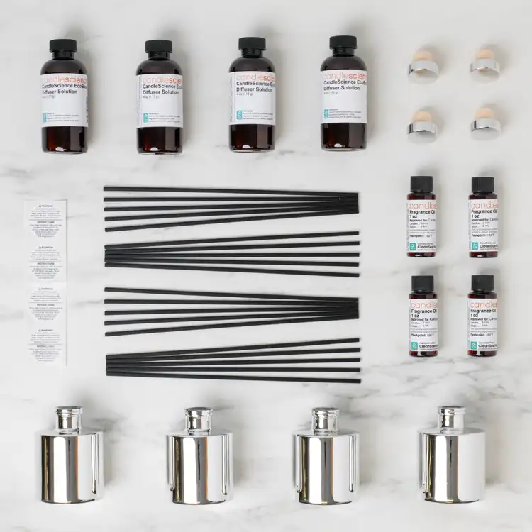 Looking down on the contents of the reed diffuser kit collection with 4 silver reed diffuser bottles, 4 eco base bottles, a set of black fiber reeds, on a white background
