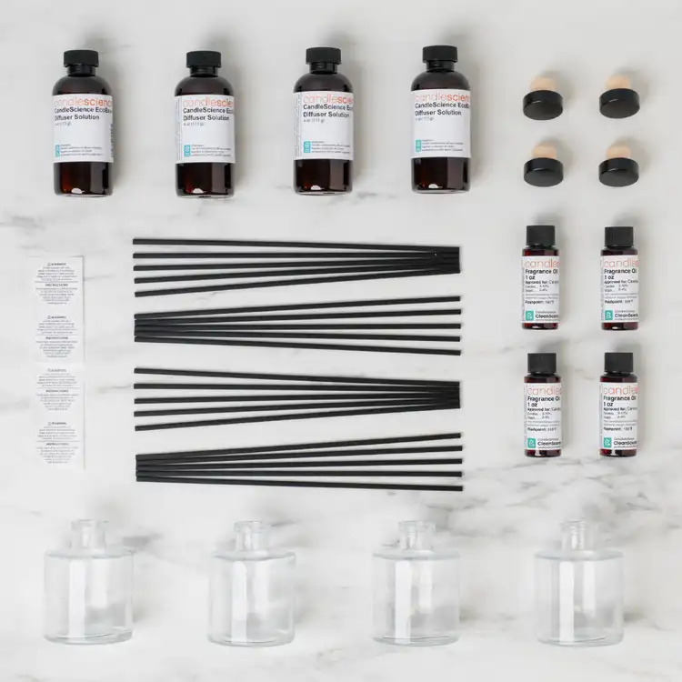 Looking down on the contents of the reed diffuser kit collection with 4 clear reed diffuser bottles, 4 eco base bottles, a set of black fiber reeds, on a white background
