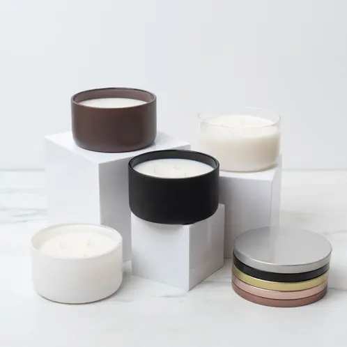 A Clear, Matte White, Matte Black, and Matte Mocha Calista Jar on risers with matching lids stacked to the side. 