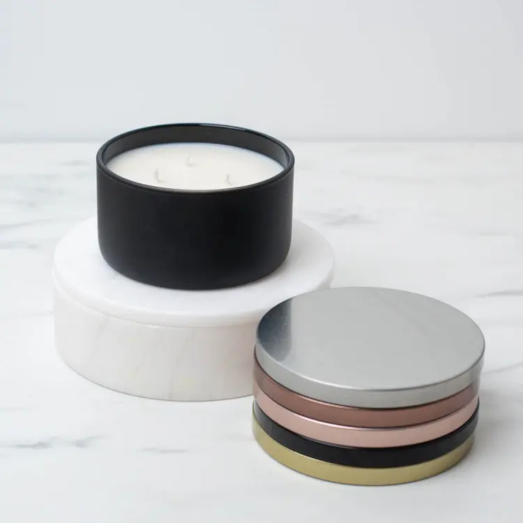 Matte Black Calista Tumbler Jar on a white riser with metal flat lids stacked beside it.