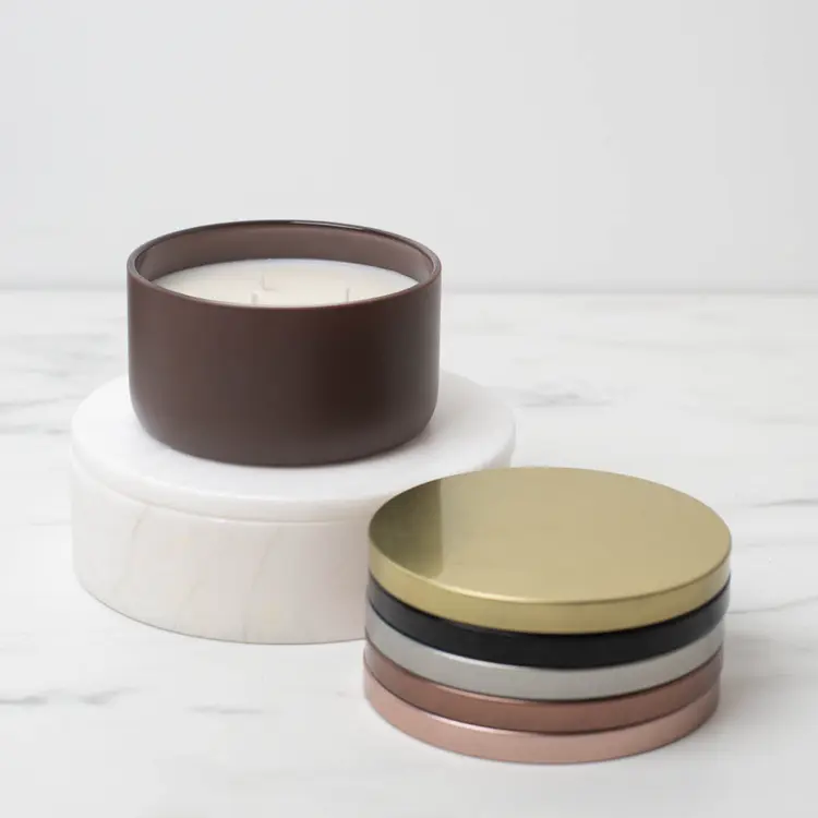 Matte Mocha Calista Tumbler Jar on a white riser with metal flat lids stacked beside it.