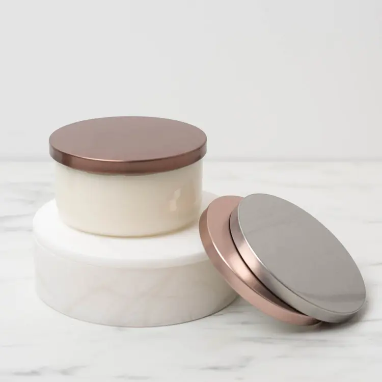 Clear Calista Tumbler Jar with Bronze Metal Flat Lid on a white riser with metal flat lids stacked beside it.