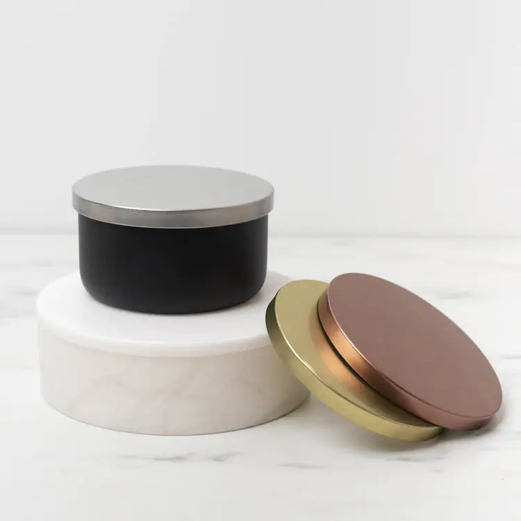 Matte Black Calista Tumbler Jar with Silver Metal Flat Lidon a white riser with metal flat lids stacked beside it.