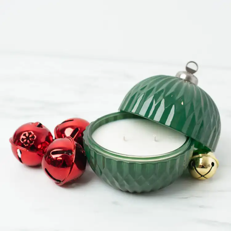 Green Glass Ornament Jar with lid partially off on marble countertop with red and gold bells