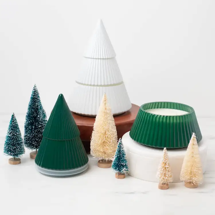 White Glass Tree Jar on a marble countertop with decorative pine trees on a wooden base.