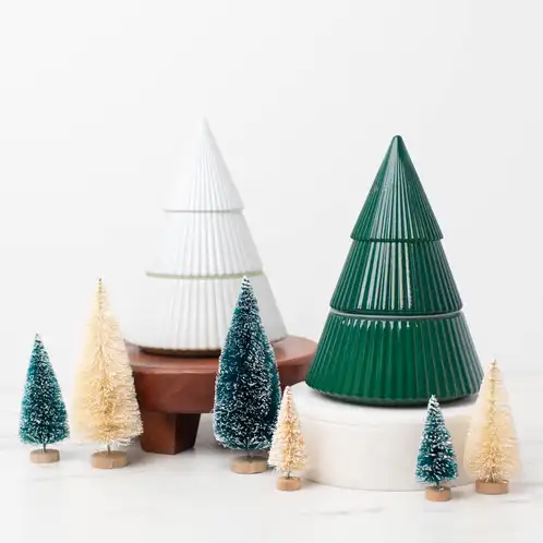 White and Green Glass Tree Jar on a marble countertop with decorative pine trees on a wooden base.