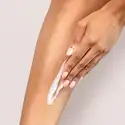 A hand rubbing Stephenson Aloe and Shea Unscented Lotion Base on a leg