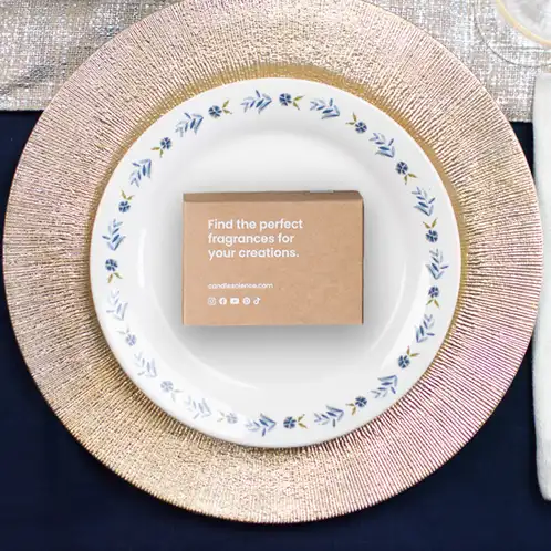 A fragrance flight box on a white plate with blue flowers around the edge