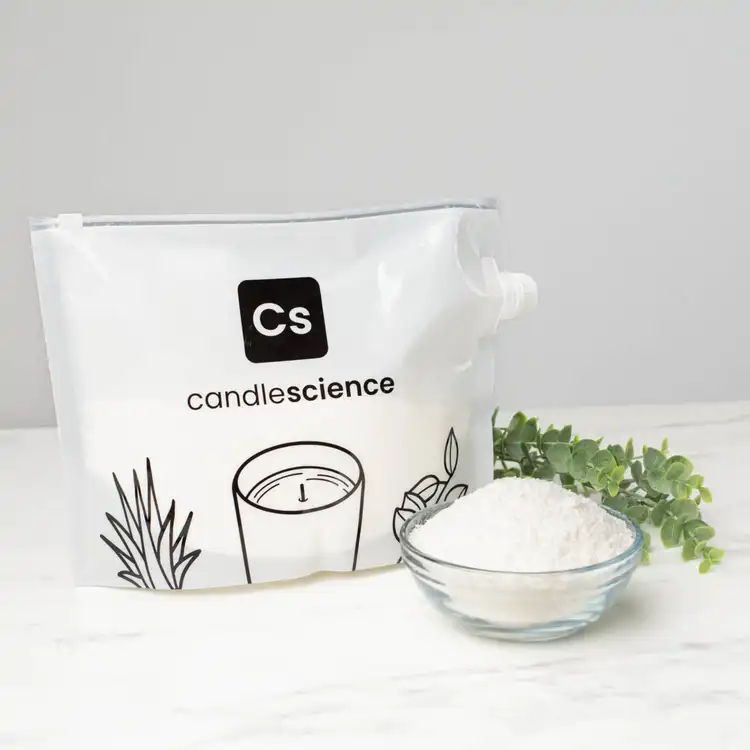 A heat-safe bag filled with SimplySoy wax beside a clear bowl of wax on a white marble countertop.