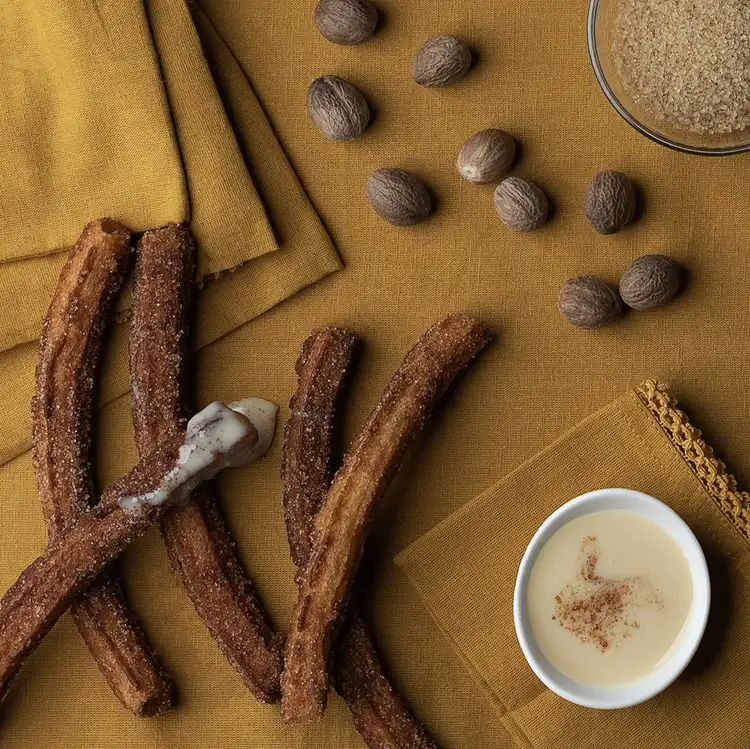 A variety of spices like cinnamon sticks on a tablecloth to showcase Golden Churro Fragrance Oil