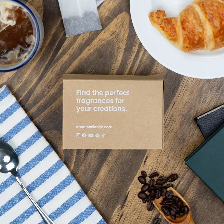 A fragrance flight box made of kraft paper that reads "Find the perfect fragrances for your creations" on a kitchen table.