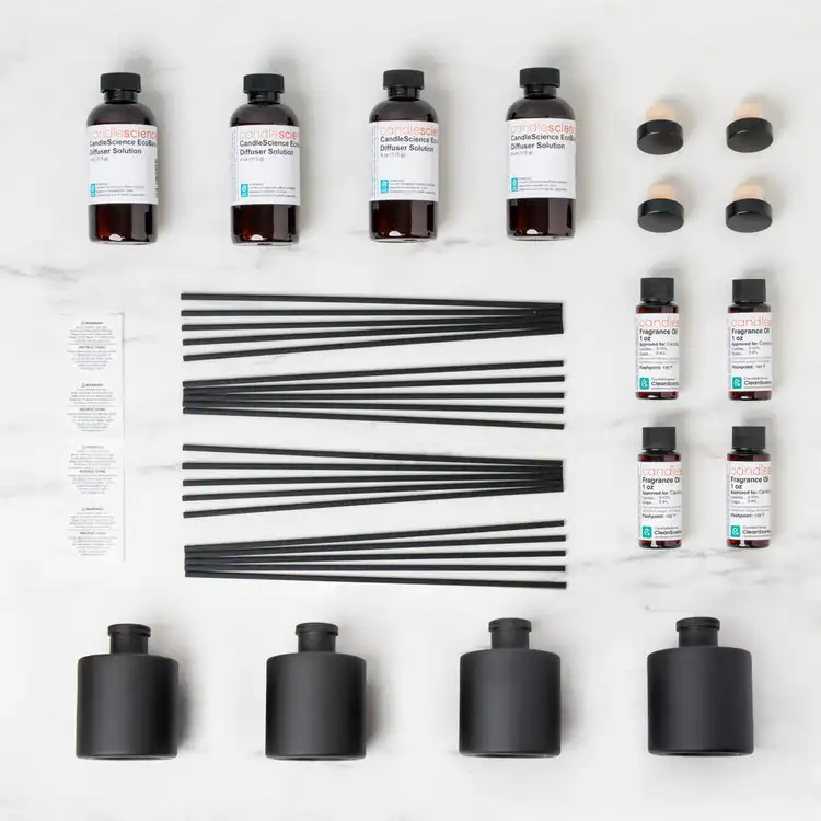 Looking down on the contents of the reed diffuser kit collection with 4 matte black reed diffuser bottles, 4 eco base bottles, a set of black fiber reeds, on a white background