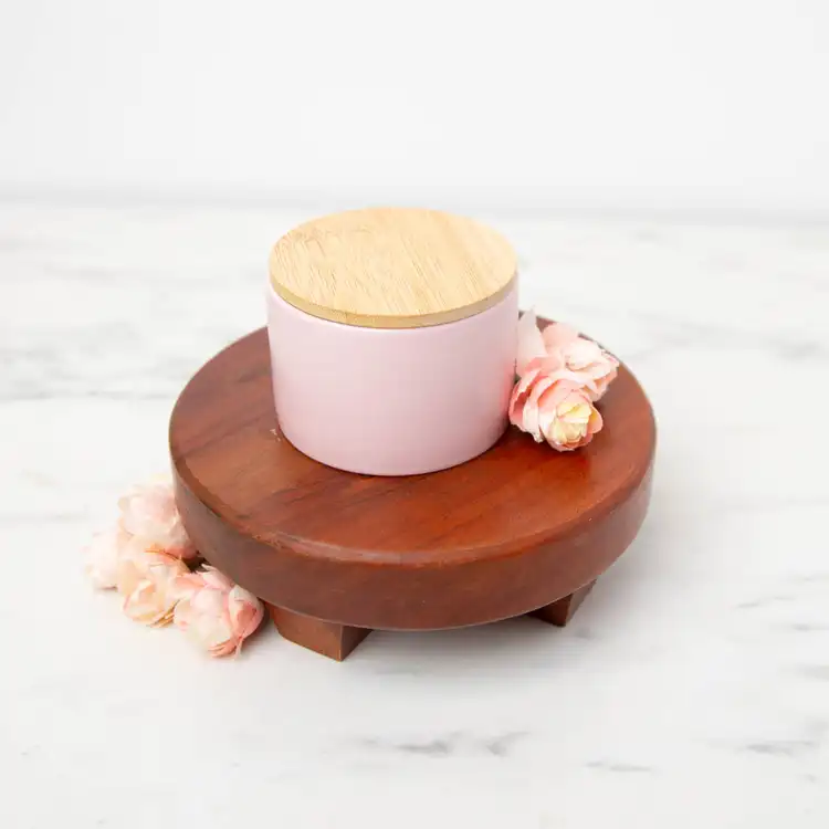 Mini Blush Modern Ceramic Tumbler with a bamboo lid on a wooden pedestal with rose buds scattered around the container 