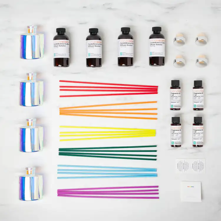 Looking down on the contents of the color burst reed diffuser kit collection with 4 prism reed diffuser bottles, 4 eco base bottles, a set of rainbow fiber reeds, on a white background