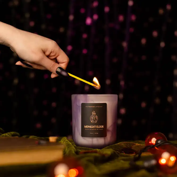 Frosted Purple Swirl Sonoma on a dark, gothic background with a hand in frame lighting the candle
