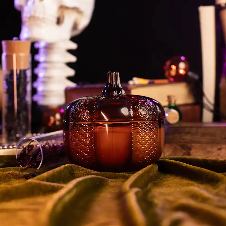 Amber Heirloom Glass Pumpkin Jar filled with a candle in a gothic setting
