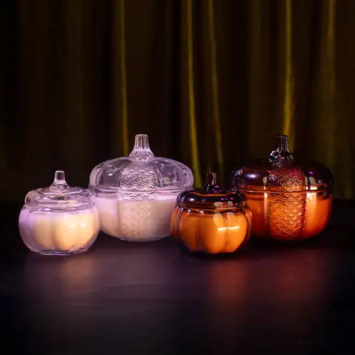 Heirloom Glass Pumpkin Jar beside Amber Heirloom Glass Pumpkin Jar on a dark and moody background. Mini clear and amber pumpkins sit beside the heirloom pumpkins