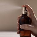 An elegant amber perfume bottle with a soft gold top spraying perfume